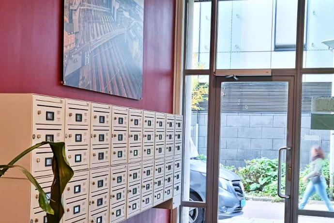 Postkasse system med app og redigerbare skilt HomeSOlution anlegg på rød vegg i en oppgang FOTO