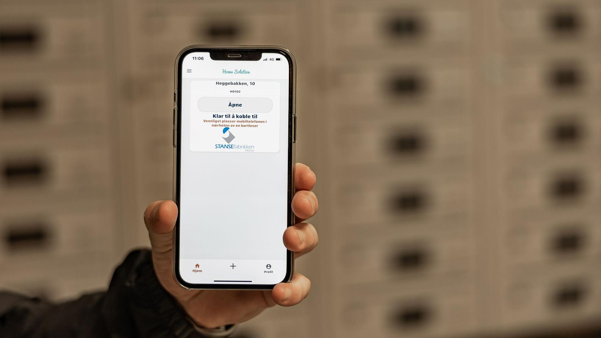 Hånd som holder en mobiltelefon med app for å åpne en postkasse med elektronisk lås FOTO