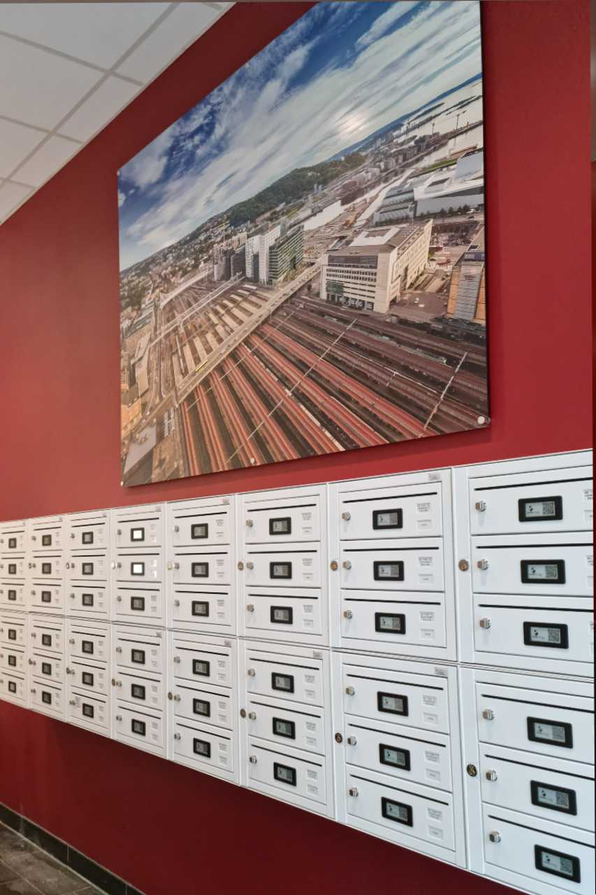 Innendørs postkasser med elektroniske låser og navneskilt, rød vegg, veggbilde FOTO