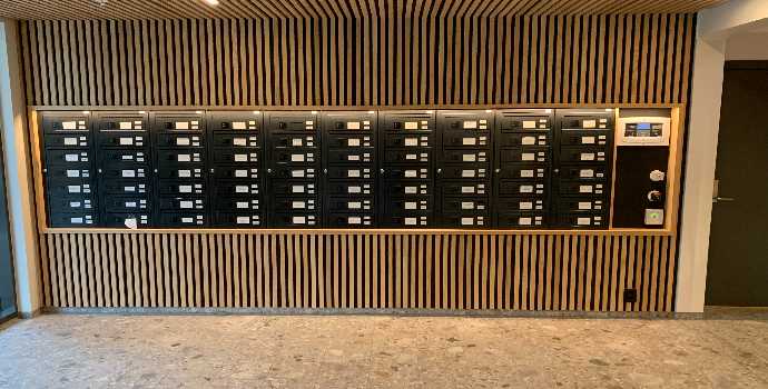 Innendørs postkasser med elektroniske låser, vegg med trespiler FOTO