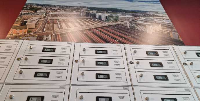 Innendørs postkasser med elektroniske låser og navneskilt, rød vegg, veggbilde FOTO