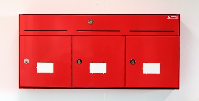 Innendørs postkasser i rød farge, hvit vegg FOTO